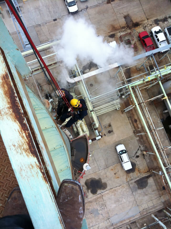 Profissional de acesso por cordas trabalhando em estrutura industrial